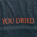 Close-up van de rood geborduurde "YOU DRIED" letters